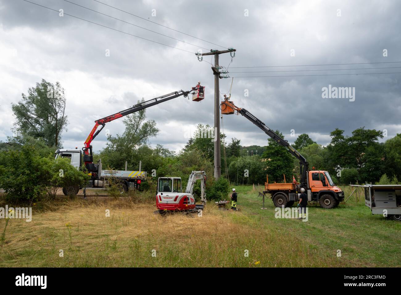 Asweiler, Germania. 12 luglio 2023. I dipendenti di un fornitore di servizi di una società di servizi pubblici lavorano dopo la tempesta su un palo di alimentazione danneggiato da una tempesta il giorno prima. Ad Asweiler, nel comune di Freisen (distretto di St. Wendel), una tempesta ha sviluppato un notevole potere distruttivo il martedì sera e infuriato in un'andana di circa 100 metri, secondo il centro di situazione della polizia. Il capo del controllo dei disastri nel distretto assume un tornado. Credito: Harald Tittel/dpa/Alamy Live News Foto Stock