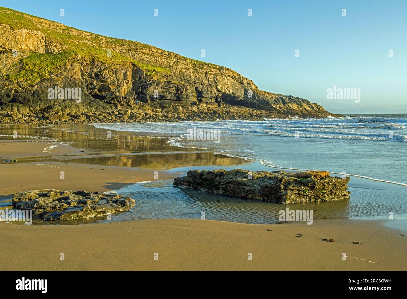 Dunraven Bay si affaccia a est in una serata di sole di maggio con il sole basso che dona un soffice bagliore ai suoi dintorni Foto Stock
