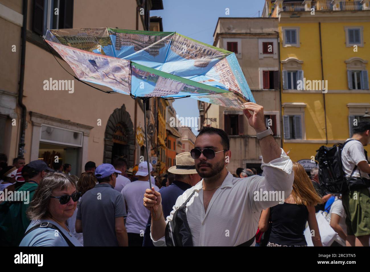 Roma, Italia. 12 luglio 2023 Un turista si rifugia dal sole caldo con un ombrello rovesciato mentre Roma sperimenta temperature elevate. Il Ministero della salute italiano ha emesso un allarme rosso ondata di calore per otto grandi città in Italia, in quanto le temperature dovrebbero ribaltarsi sopra i 40°C/104F.. Credit amer ghazzal/Alamy Live News Foto Stock