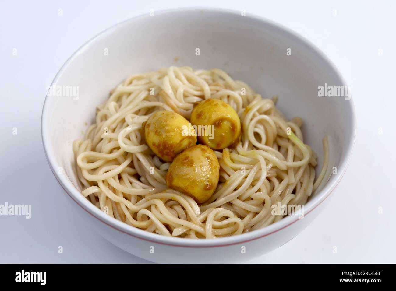 Spaghetti istantanei con condimento di uova di quaglia in un recipiente isolato su sfondo bianco con bacchette. Concetto di fast food in stile asiatico e cinese. Foto Stock