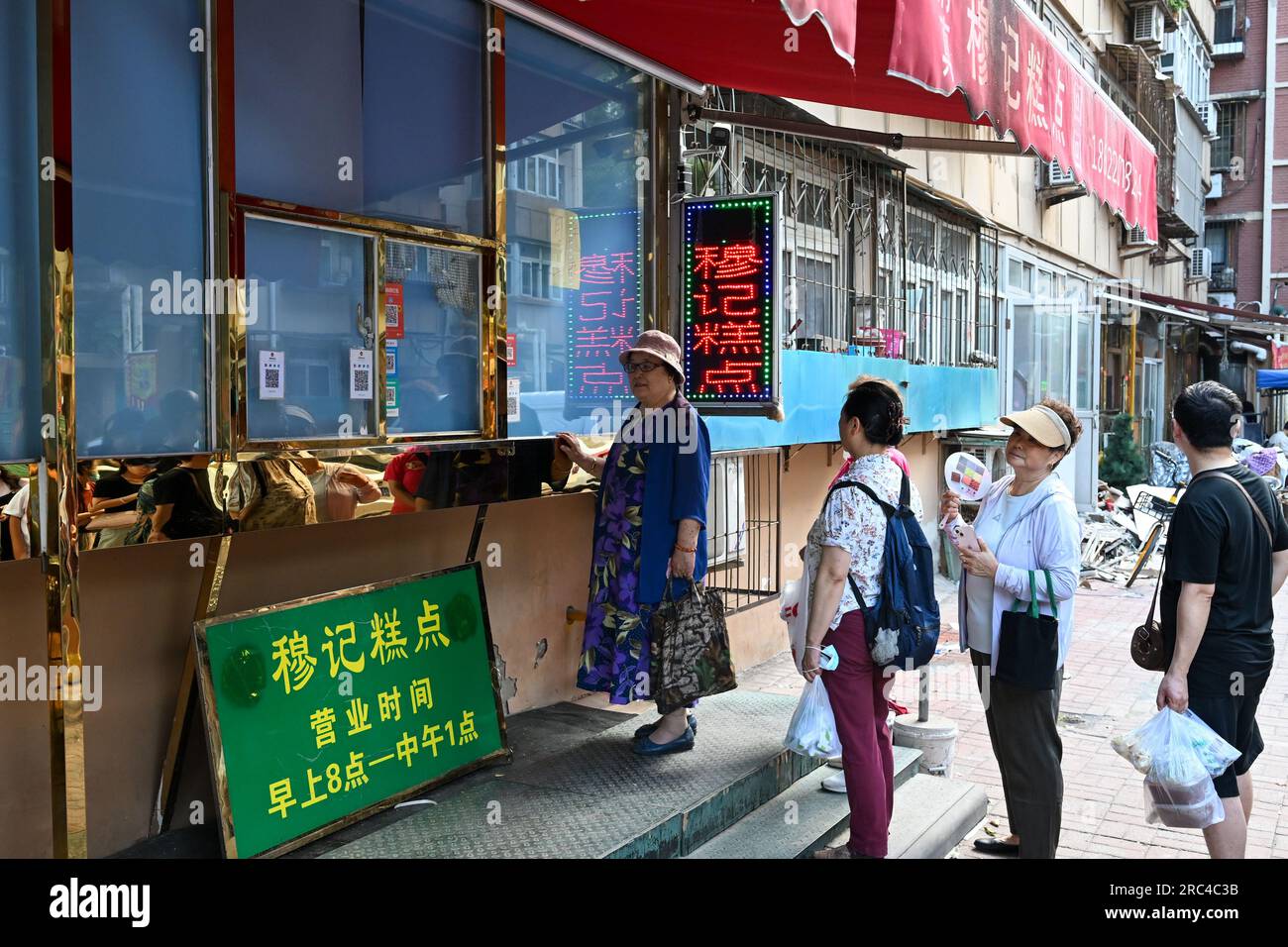 Tianjin, Cina. 10 luglio 2023. La gente si mette in fila in un negozio per la colazione prima della sua apertura nell'angolo nord-occidentale di Tianjin, nella Cina settentrionale, il 10 luglio 2023. Il Northwest Corner prende il nome dalla sua posizione nell'angolo nord-ovest della città vecchia di Tianjin. Al mattino, molti turisti che parlano dialetti diversi trascinano qui le loro valigie per fare colazioni con le caratteristiche di Tientsin. Crediti: Sun Fanyue/Xinhua/Alamy Live News Foto Stock