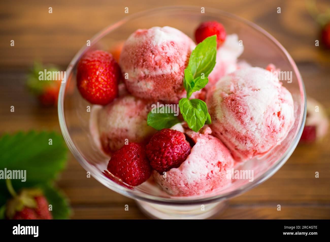 Palle di gelato alla fragola fatto in casa in una ciotola su un tavolo di legno. Foto Stock