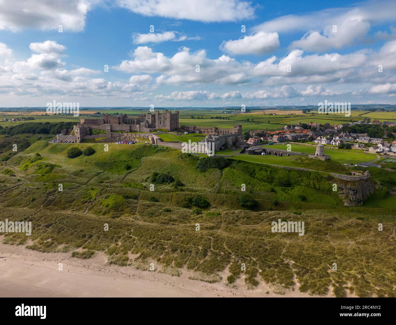 Foto aerea del castello di Bamburgh sulla splendida costa di Northumberland, Inghilterra. Il castello è circondato da dune, spiaggia e mare Foto Stock