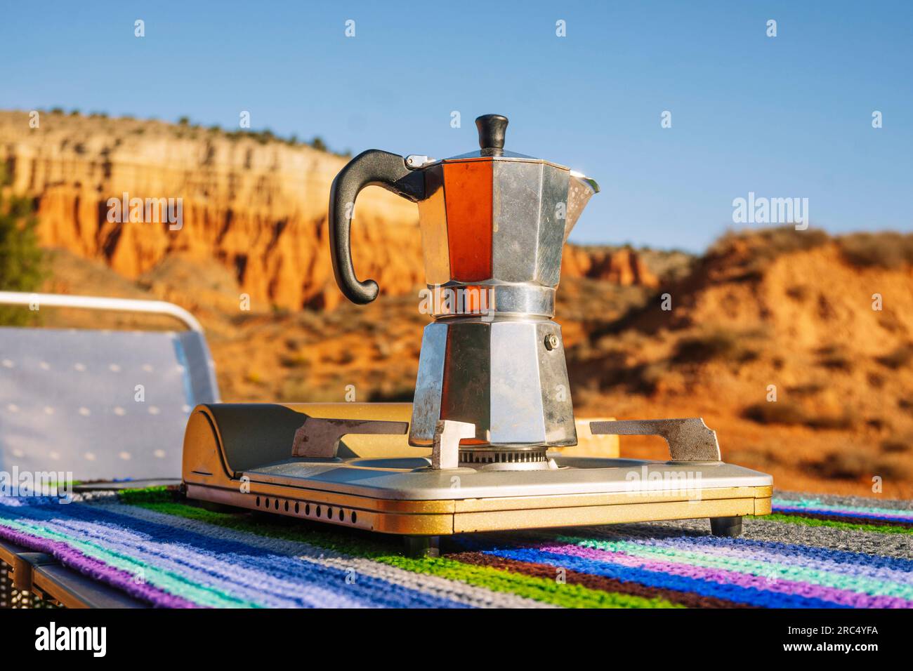 Campeggiare caffettiera metallica moka su una stufa portatile a gas su un  tavolo colorato nella natura del canyon Rojo Teruel Spagna Foto stock -  Alamy