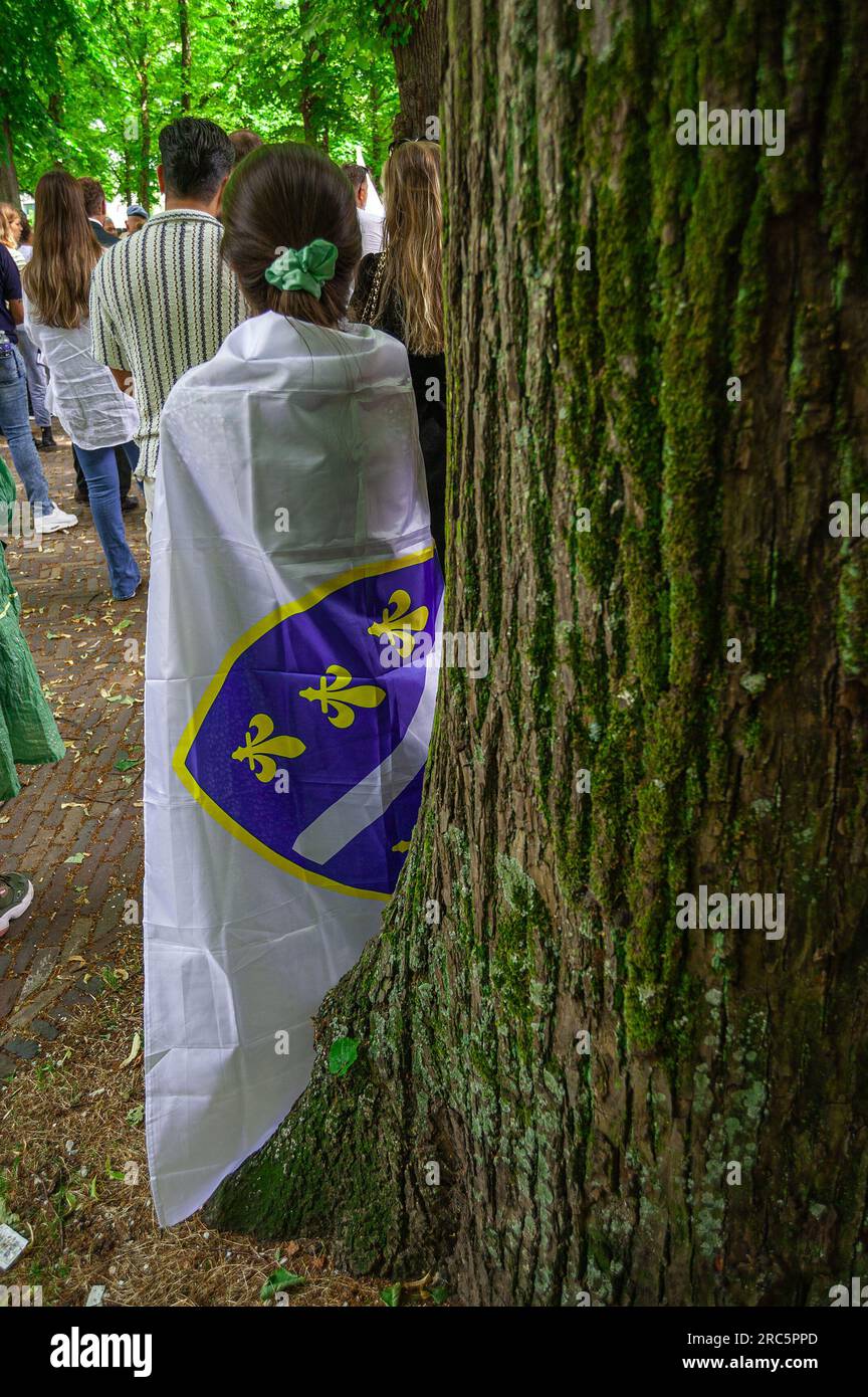 11 luglio 2023, l'Aia, Paesi Bassi: Una donna si trova ad un albero drappeggiato nella bandiera della Repubblica di Bosnia-Erzegovina sul Voorhout di Lange a l'Aia per commemorare il massacro etnico del 1995 di oltre ottomila vittime del genocidio di Srebrenica. Dal 1997, il genocidio di Srebrenica si tiene ogni anno l'11 luglio a Het Plein a l'Aia. Un cambio di sede per l'evento di oggi che si tiene a Lange Voorhout. In questo giorno, più di ottomila vittime del genocidio di Srebrenica sono commemorate. Queste persone furono uccise nel 1995 dai nazionalisti radicali serbi e B Foto Stock