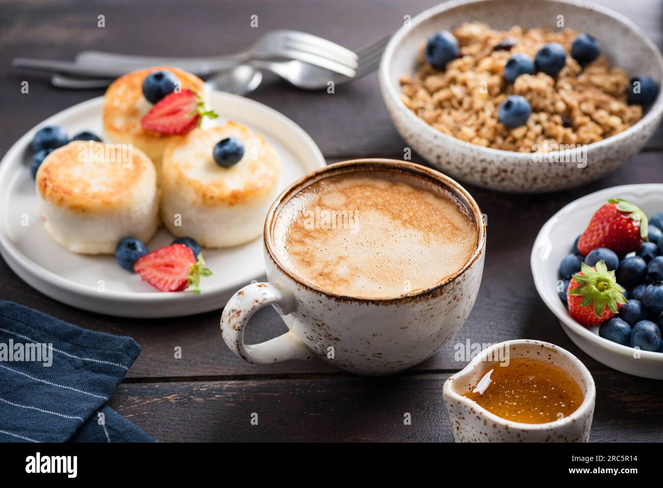 Cappuccino al caffè, frittelle al formaggio e muesli per colazione. Vista ravvicinata Foto Stock