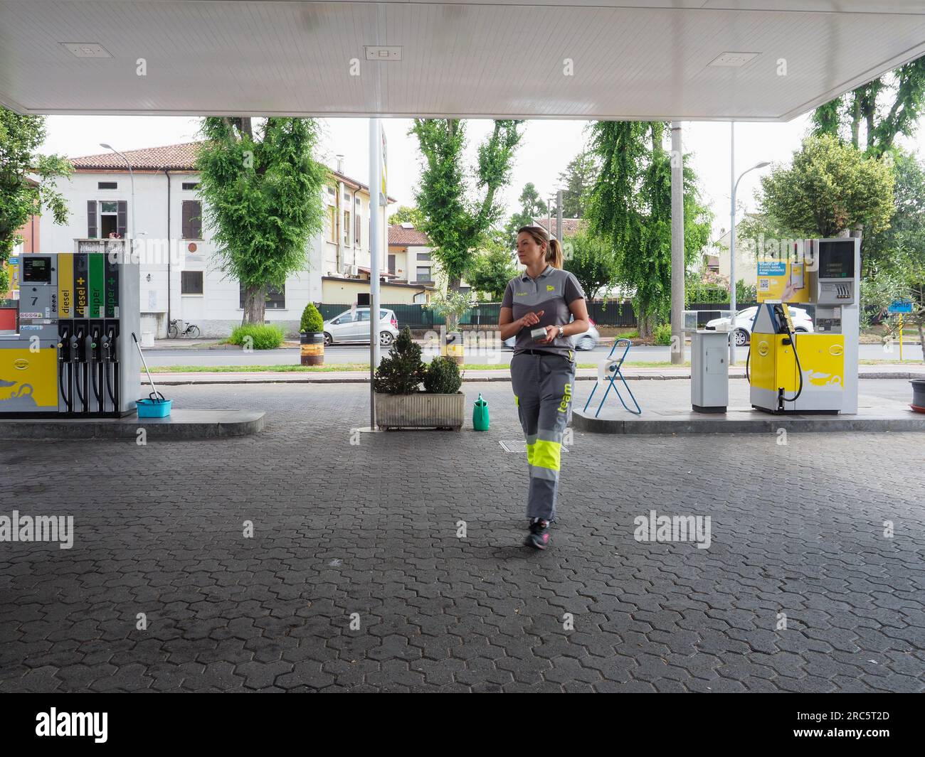 Cremona, Italia - 3 luglio 2023 donna addetto alla stazione di servizio che accetta pagamenti con carta di credito da clienti all'aperto vicino a pompe di benzina Foto Stock