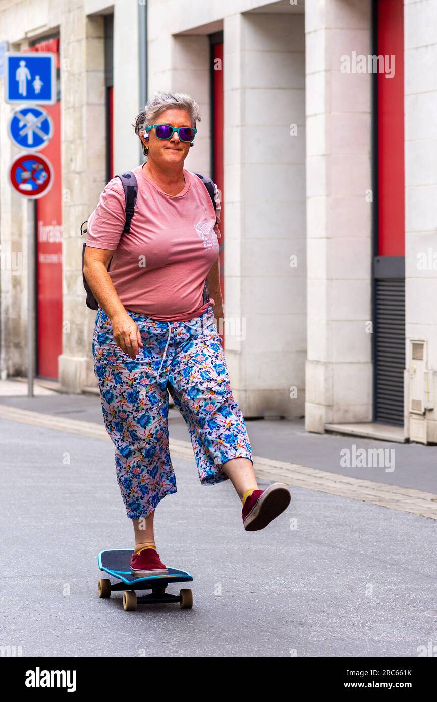 Donna matura skateboard attraverso il centro città - Tours, Indre-et-Loire (37), Francia. Foto Stock