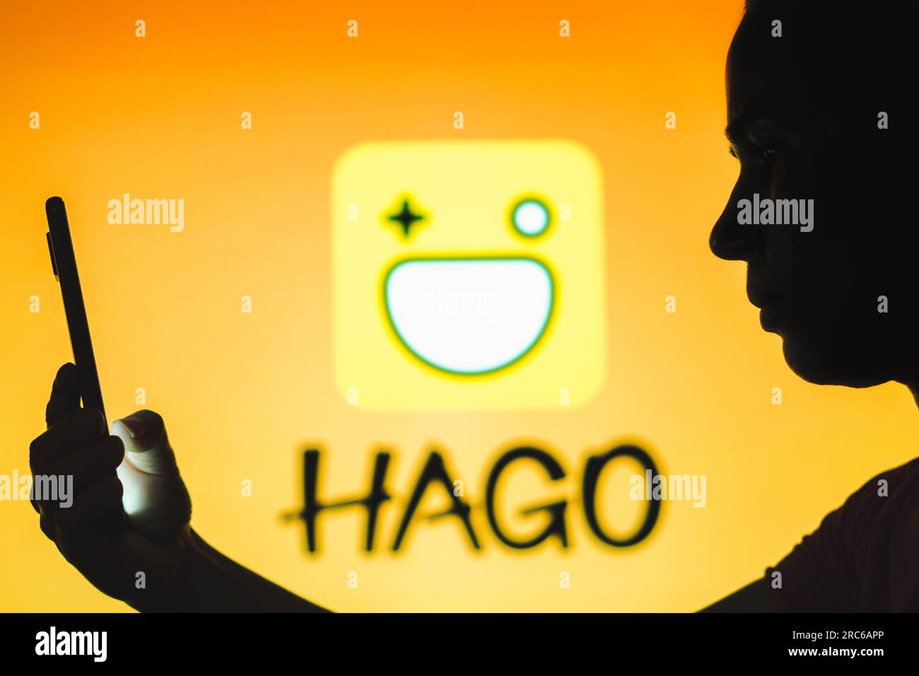 In questa foto, una persona ha uno smartphone con il logo Hago sullo sfondo. Foto Stock