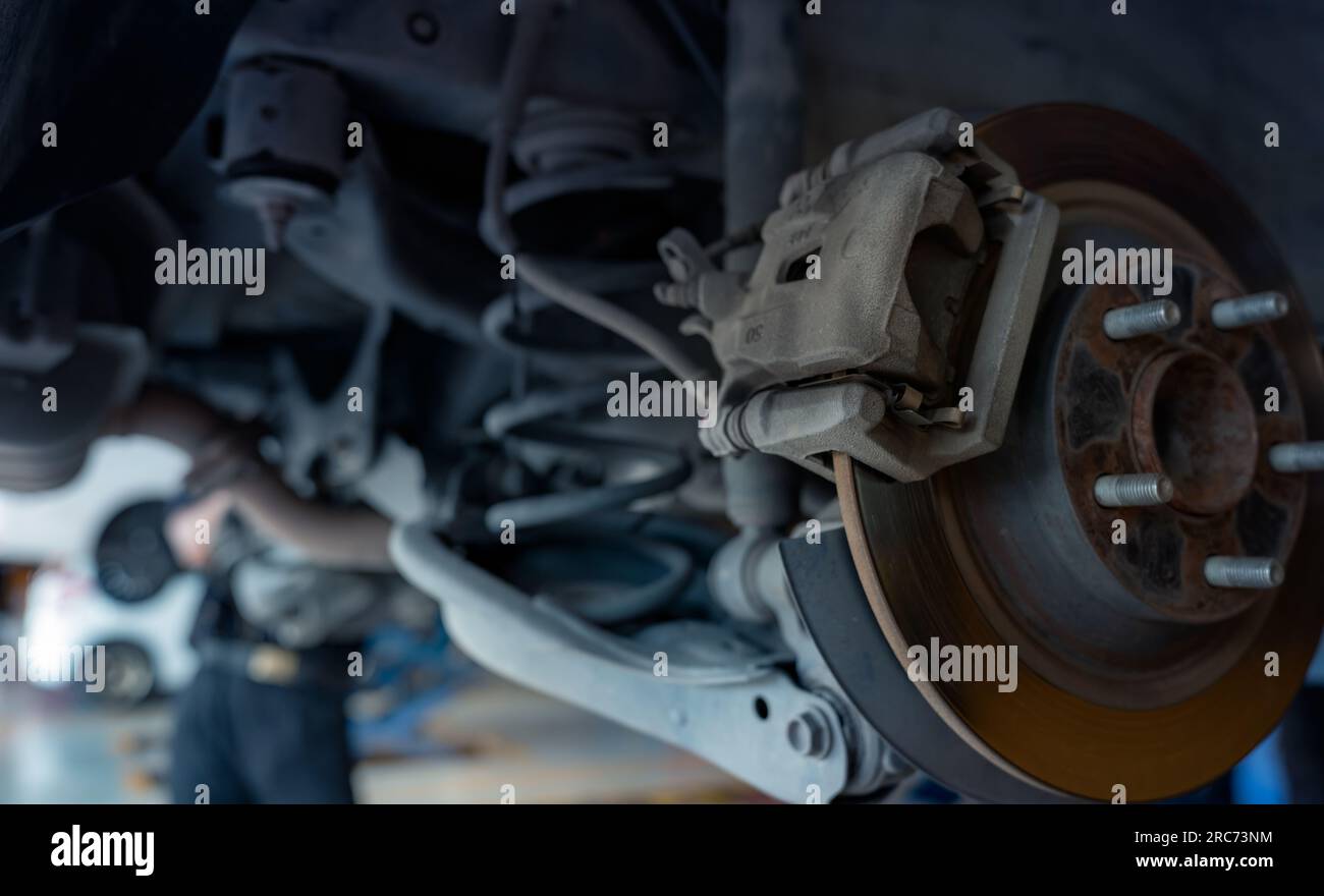 Impianto frenante a disco per auto. Sospensione della vettura in corso di sostituzione di nuovi pneumatici in officina. Controllo meccanico del freno a disco per auto e riparazione. Rodaggio rottura disco Foto Stock