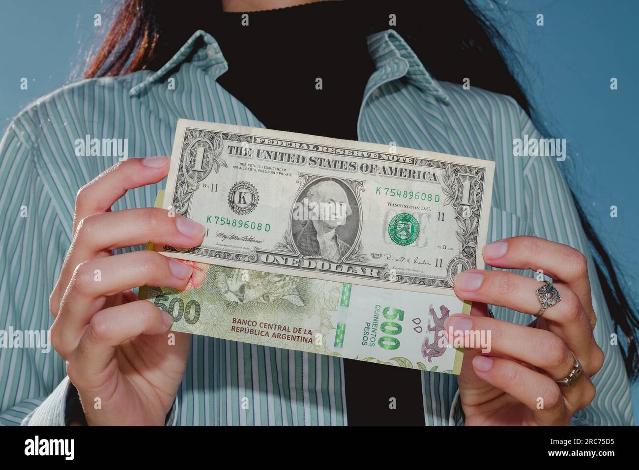 Donna che ha una banconota da un dollaro e 500 pesos argentini. Concetto di inflazione e aumento del dollaro in Argentina Foto Stock