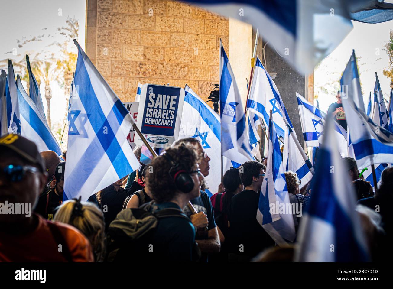 Gerusalemme, Israele. 11 luglio 2023. I manifestanti sventolano le bandiere israeliane e tengono un cartello durante una manifestazione all'aeroporto internazionale Ben Gurion. La polizia israeliana si è scontrata con i manifestanti in mezzo a enormi manifestazioni contro i controversi piani di riforma giudiziaria del governo. Le proteste sono scoppiate dopo che un disegno di legge per rimuovere il potere della Corte Suprema di rivedere le decisioni dei ministri ha approvato la sua prima lettura in parlamento lunedì sera. Le riforme hanno polarizzato il paese, scatenando mesi di manifestazioni di massa. Credito: SOPA Images Limited/Alamy Live News Foto Stock