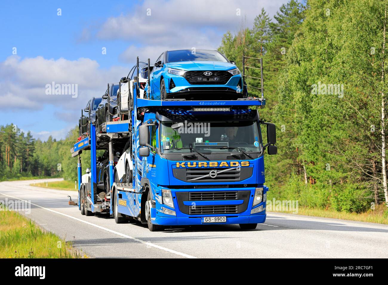 Il vettore automobilistico Blue Volvo FM di Kurbads trasporta nuove auto dal porto di Hanko verso l'interno della Finlandia in estate. Raasepori, Finlandia. 7 luglio 2023 Foto Stock