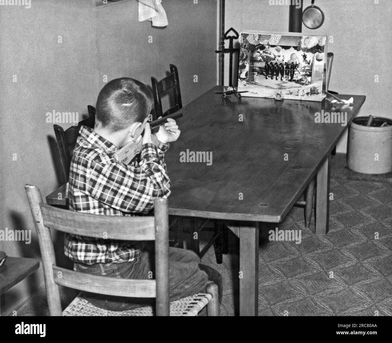 Stati Uniti: c. 1950. Un ragazzo spara a un uccello in una partita con una pistola da sughero sul tavolo della famiglia. Foto Stock