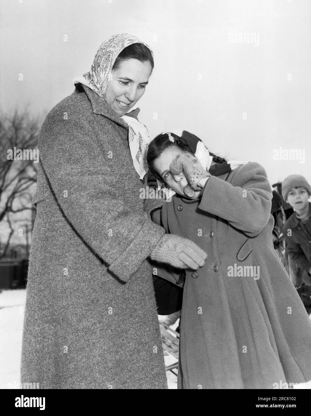 Stati Uniti, c. 1950 Una ragazza infila la lingua al fotografo mentre piange ed è confortata da sua madre. Foto Stock