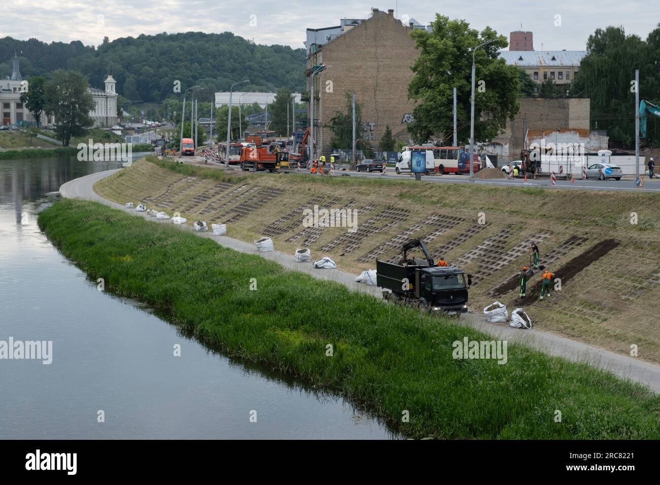 I lavoratori municipali formano la parola "slava ucraina" (Gloria all'Ucraina) con fioriere contro una strada lungo il fiume Vilnia Foto Stock