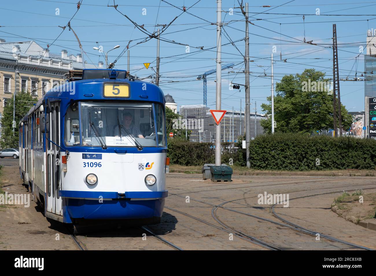 Trasporti pubblici riga. Tram elettrico vecchio blu e bianco visto dalla parte anteriore sotto un labirinto di cavi sospesi Foto Stock