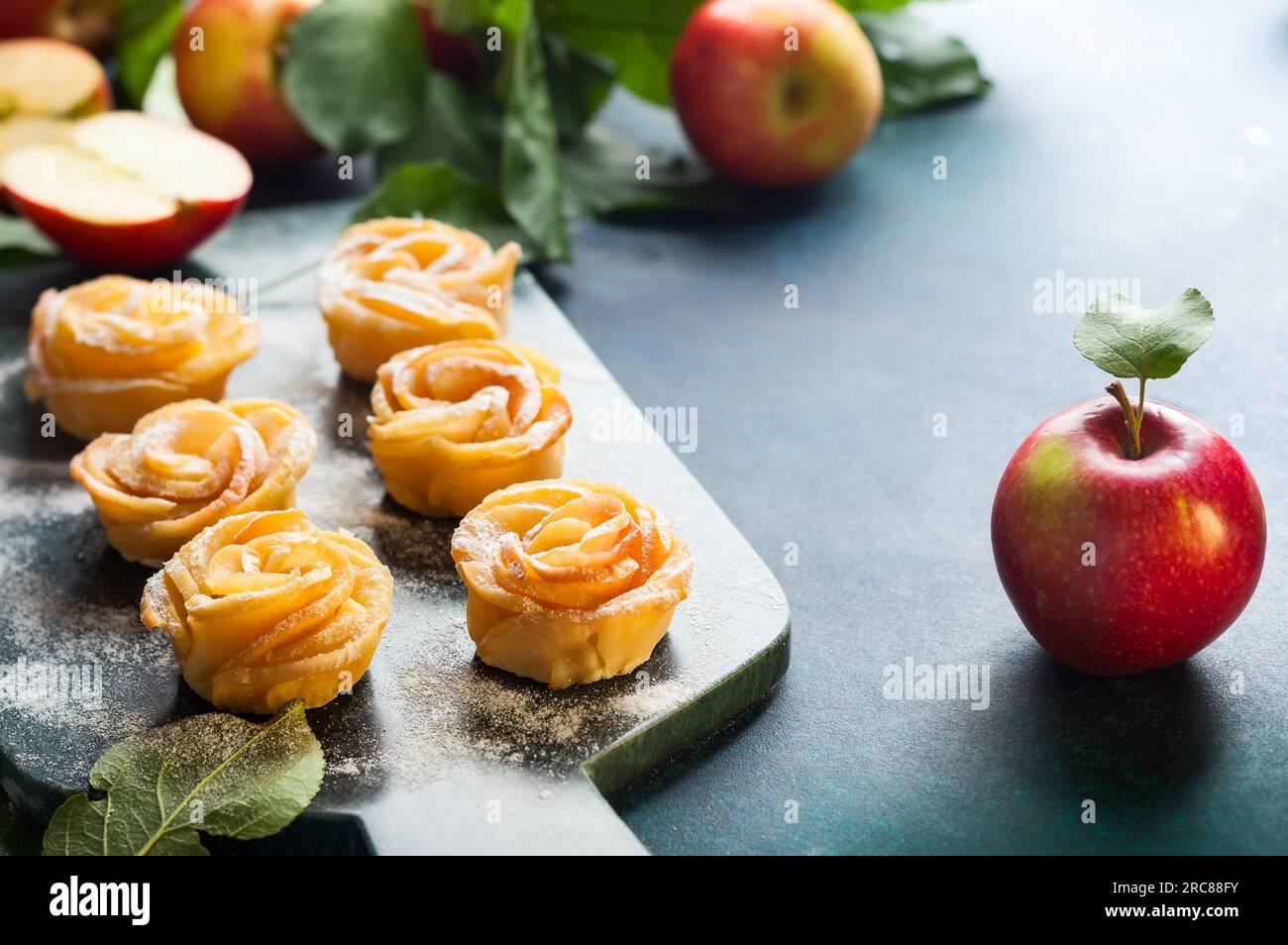 Mini crostate con rose di mele e zucchero a velo sul tagliere di pietra. Foto Stock