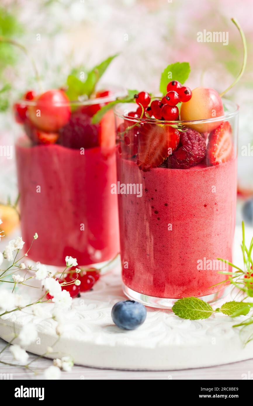 Mousse al gusto di frutti di bosco condita con frutti di bosco freschi in bicchieri. Dessert estivo con fragole, lamponi, ribes rosso, ciliegia e mirtillo Foto Stock