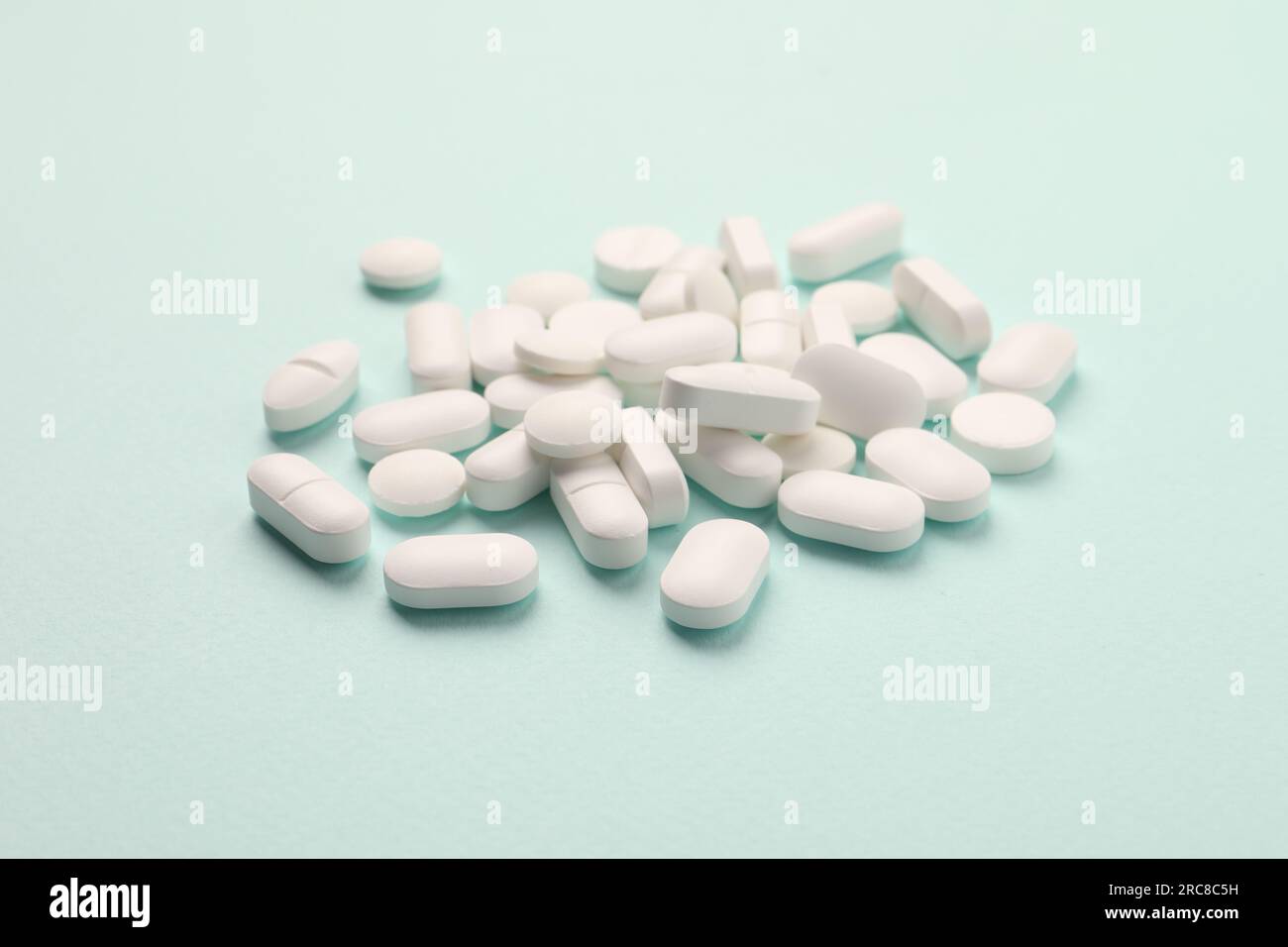 Pila di pillole bianche su sfondo menta Foto Stock