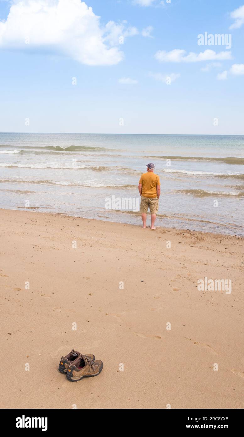 Uomo che si gode un tuffo in mare, lasciando le scarpe durante il caldo sulla spiaggia di Horsey Beach, vicino al Sea Palling, un resort costiero a norfolk. Foto Stock