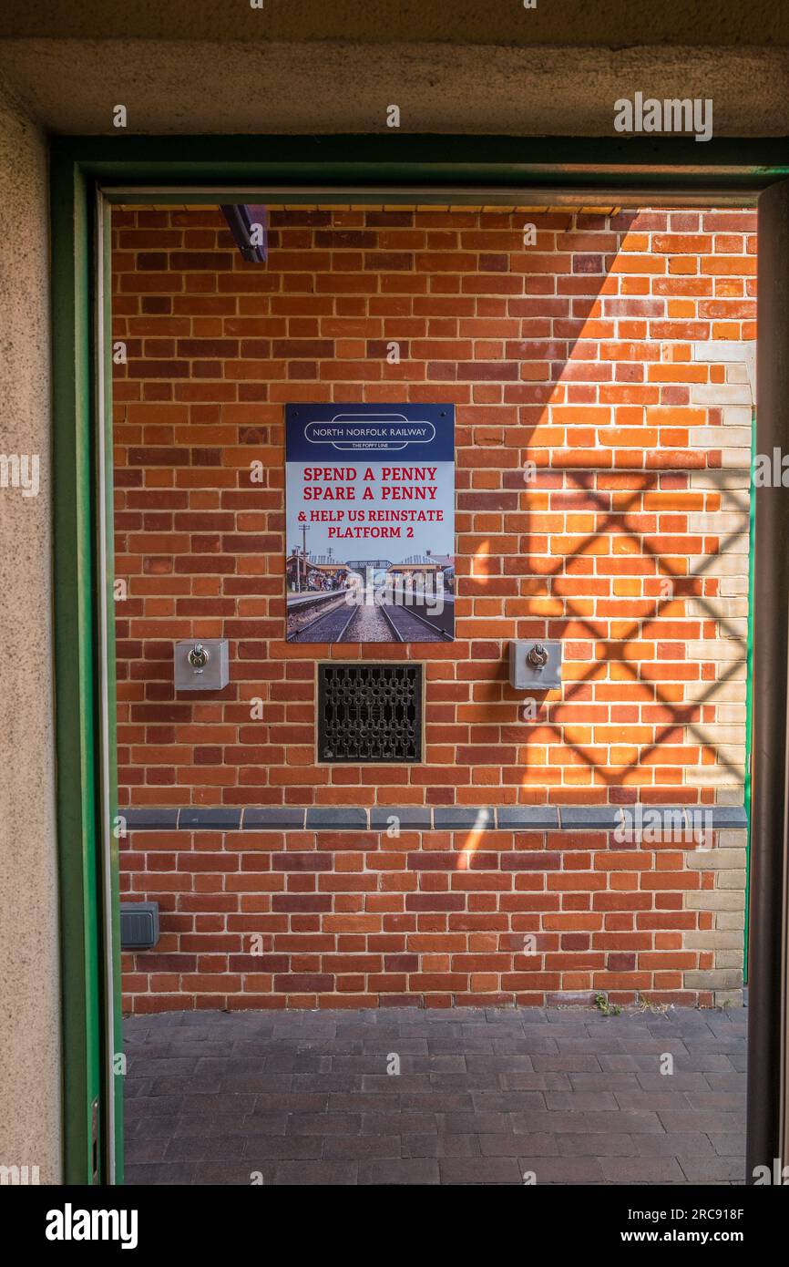 Cartello Scegli una Penny Spare una Penny appesa al muro presso la storica stazione ferroviaria vittoriana di Sheringham, Norfolk. Foto Stock