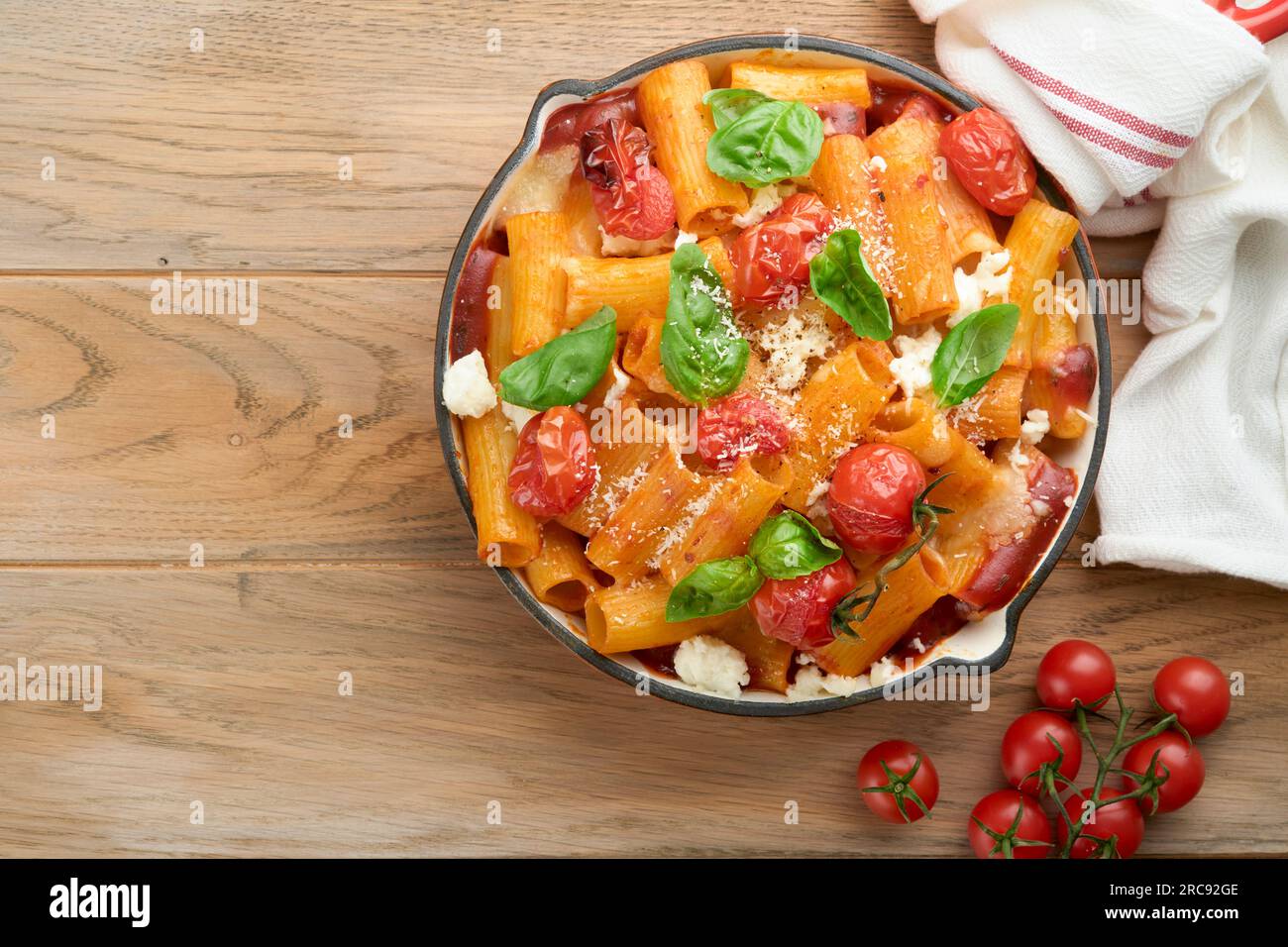 Tortiglioni di pasta con salsa di pomodoro, pomodori ciliegini al forno, mozzarella e parmigiano, basilico su fondo rustico antico. Italiano tradizionale Foto Stock