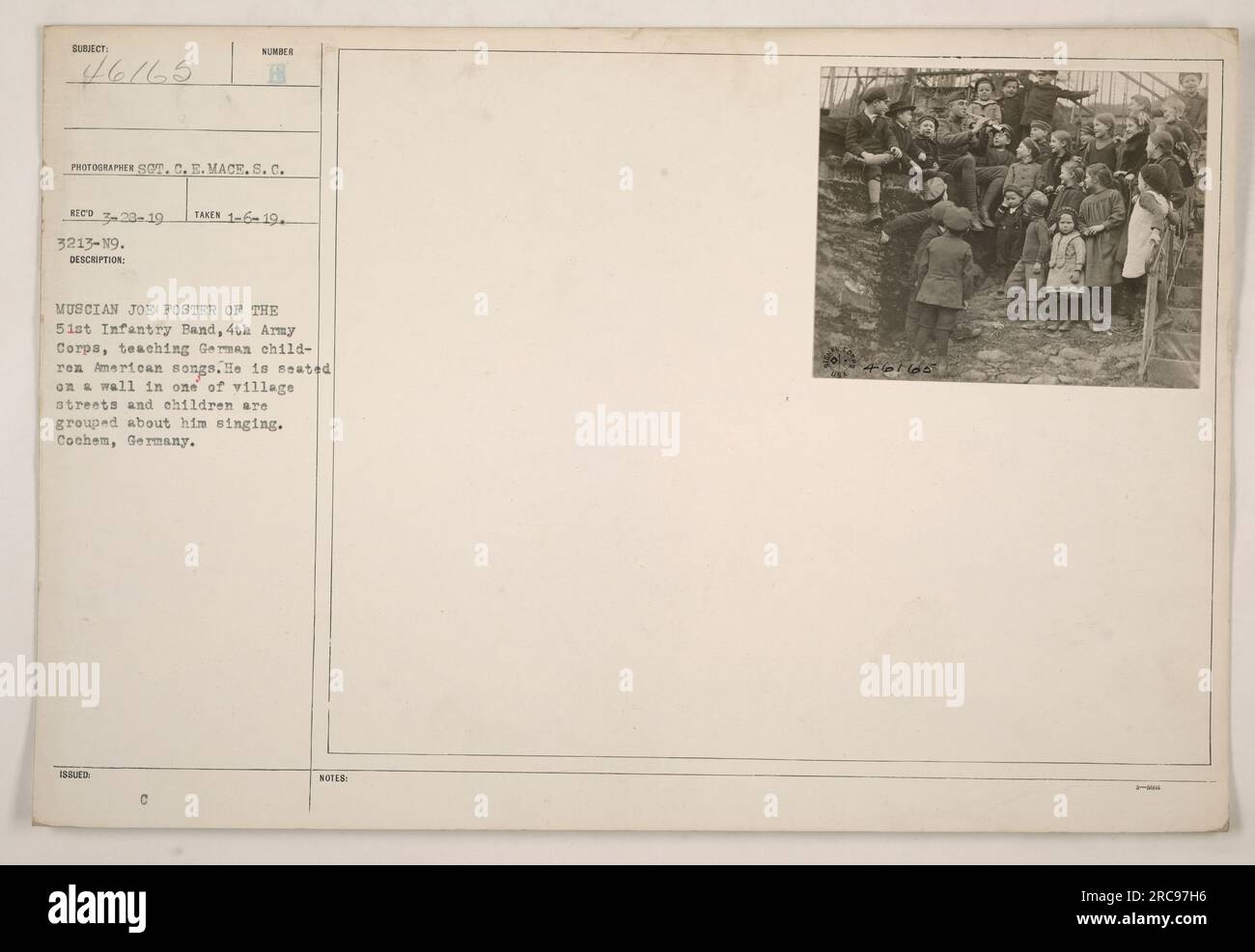 Joe Foster, un musicista della 51st Infantry Band, 4th Army Corps, è visto insegnare canzoni americane per bambini tedeschi a Cochem, in Germania. La foto è stata scattata il 23 marzo 1919 da S.C. E. Mace. Foster è seduto su un muro in una delle strade del villaggio, con bambini riuniti intorno a lui che cantano. Foto Stock