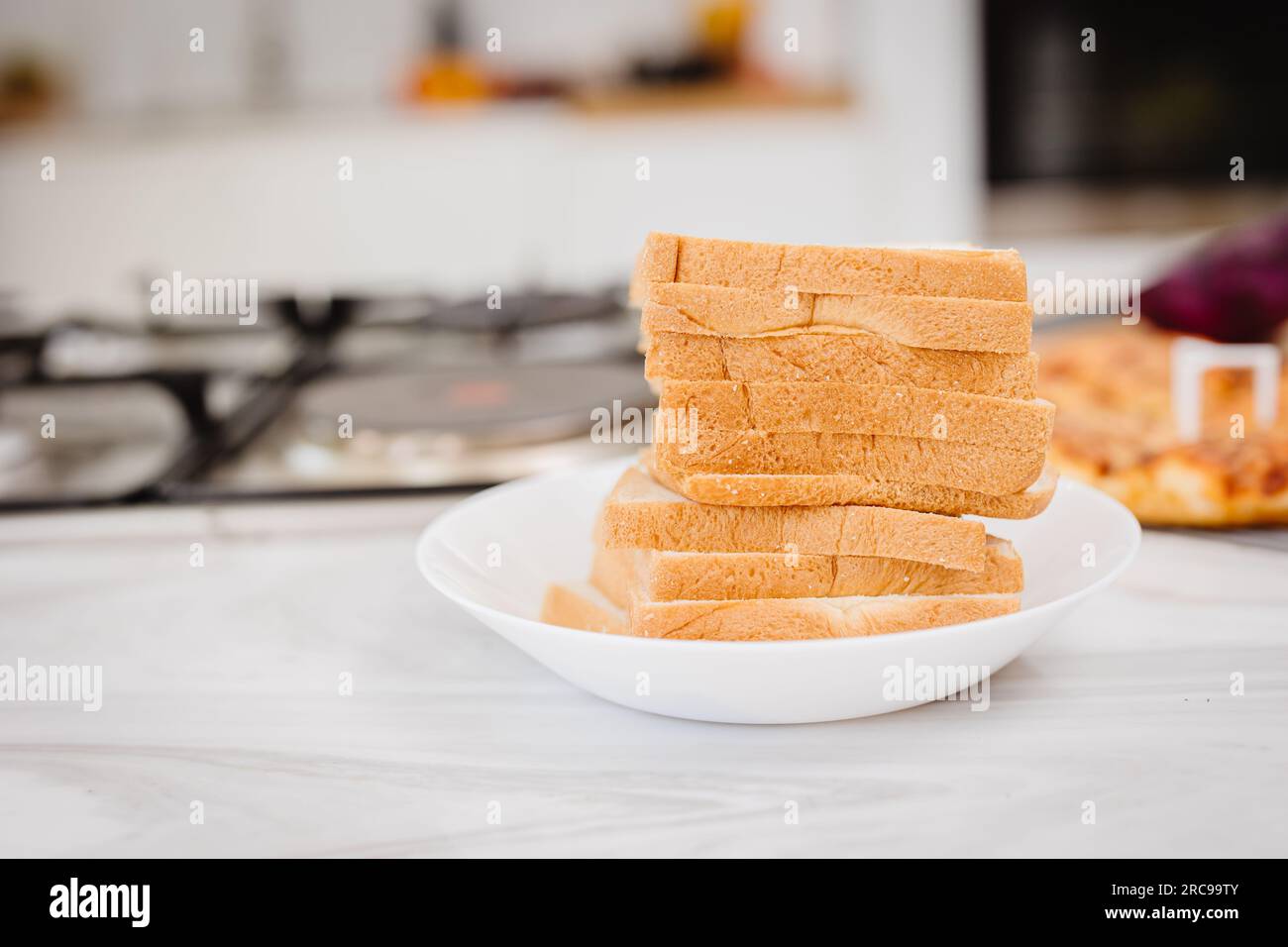 primo piano: una pila di fogli di pane a fette impilata su un piatto bianco in cucina Foto Stock