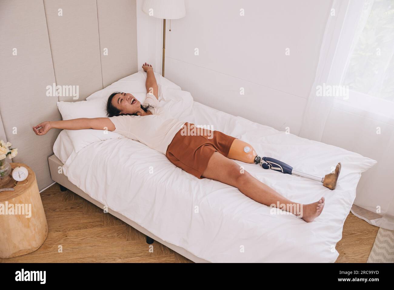 Protesi donna felice gamba bionica svegliarsi al mattino in casa adorabile letto spensierato forte sano buon mentale Foto Stock