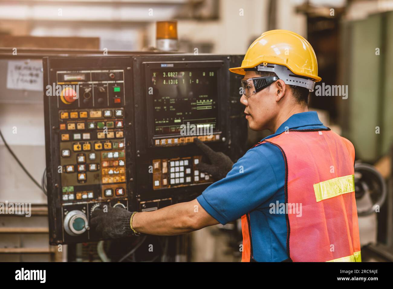 I lavoratori asiatici lavorano con la macchina per metallo CNC Tornio digitale automatizzato. Configurazione del tecnico funzionamento della fresatrice a programmazione in fabbrica. Foto Stock