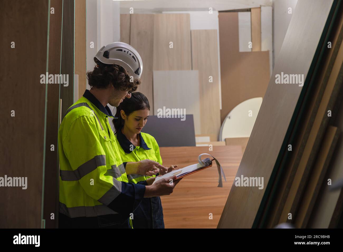 team del personale che lavora nella fabbrica dell'industria del mobile in legno che controlla l'inventario del compensato materiale di stagionatura del bordo di legno in magazzino. Foto Stock