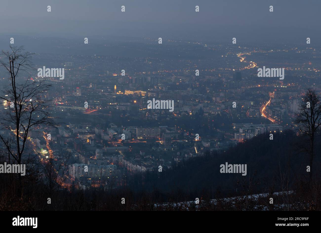 Paesaggio urbano di Banja Luka nella foschia durante il tramonto con le prime luci della città accese Foto Stock