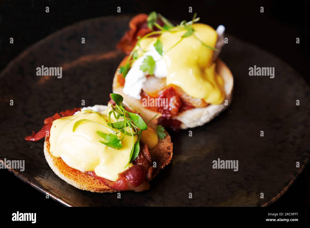 Uova alla Benedict, fatte con pancetta, condite con salsa Hollandaise e una guarnigione. Sono servite per colazione. Foto Stock