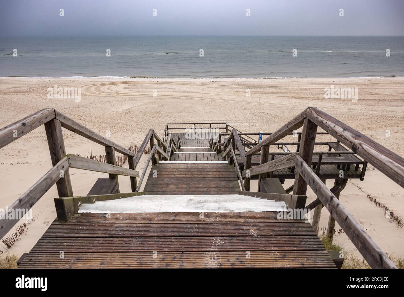 Blick von der Strandtreppe auf den Darunter liegenden, menschenleeren Weststrand von List/Sylt. Der graue Himmel hängt voller Feuchtigkeit Foto Stock