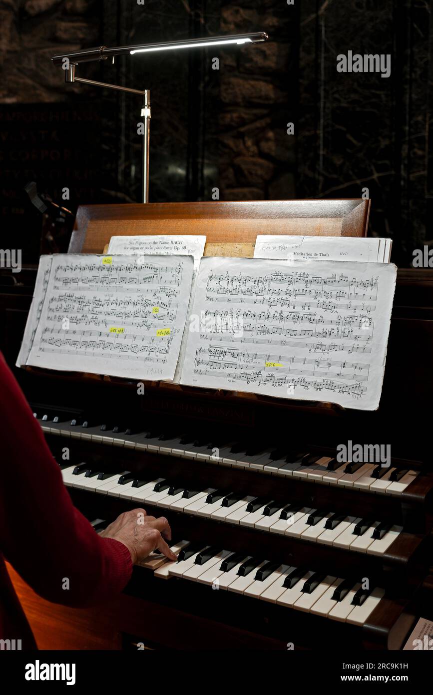 Un suonatore d'organo mentre esegue una partitura seguendo note musicali Foto Stock