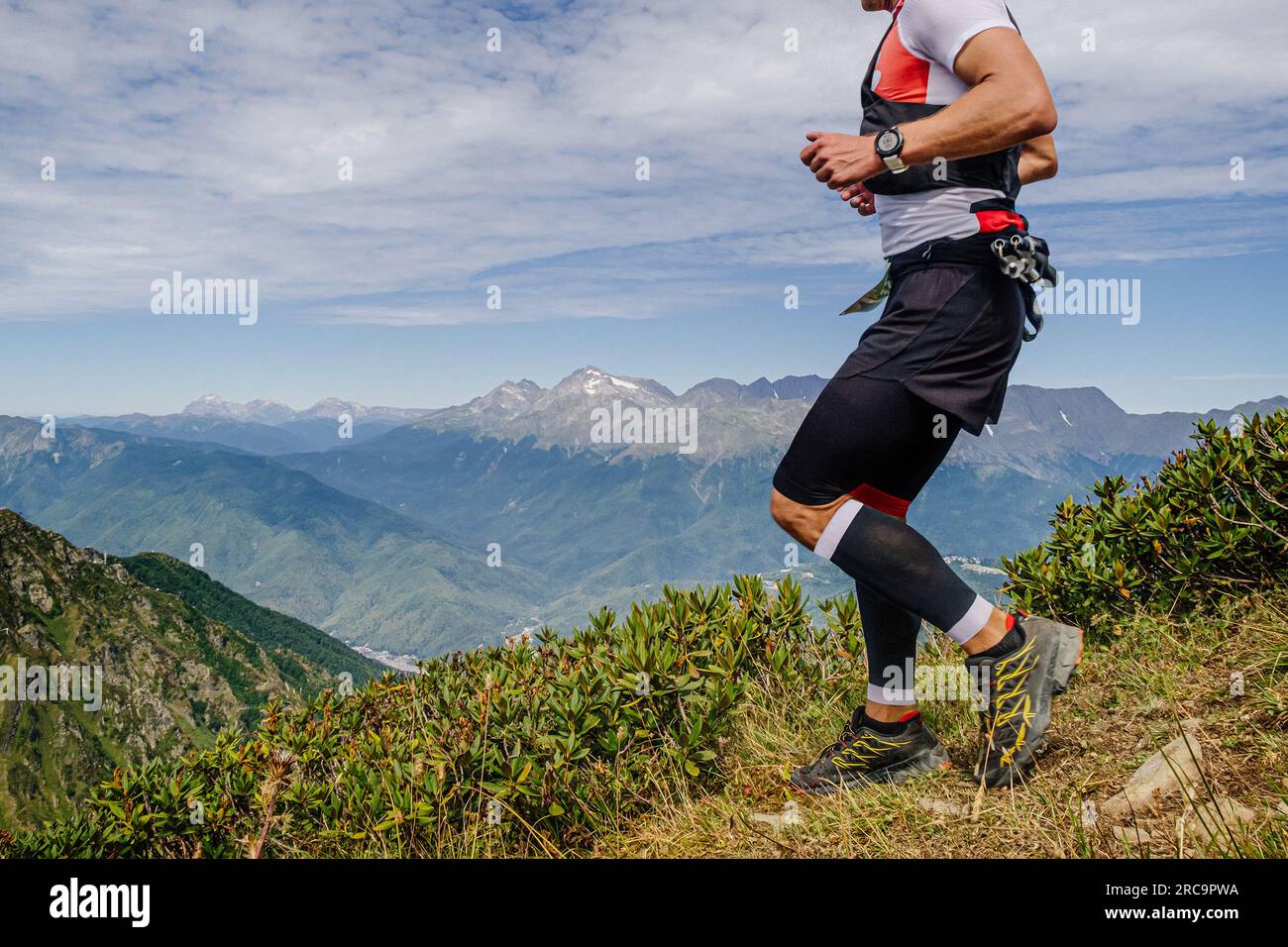 atleta maschile che corre in montagna con maniche a compressione ai piedi in una gara di maratona di montagna Foto Stock
