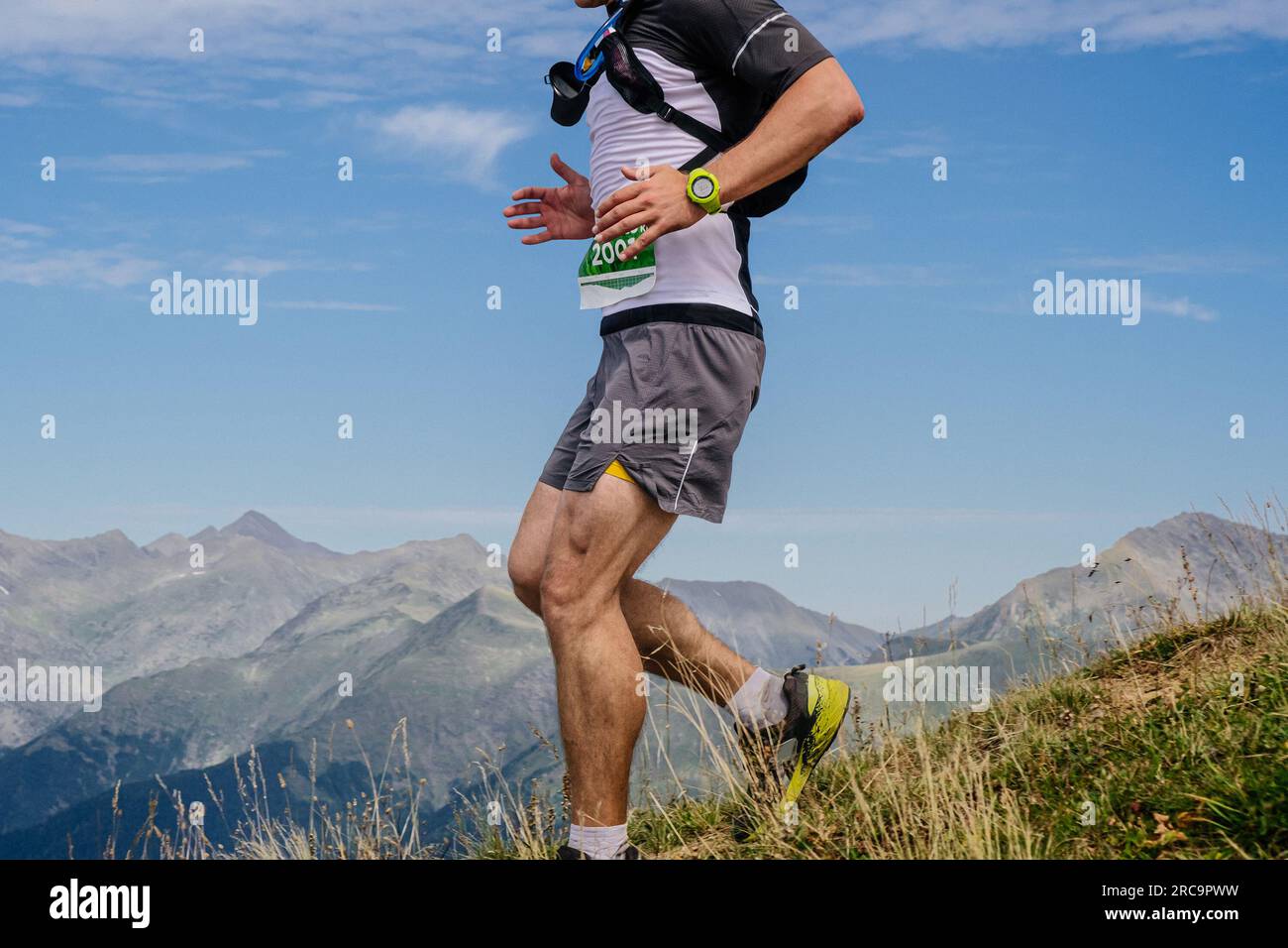 atleta femminile che corre dal fianco della montagna con leggings, maratona di montagna, cielo di fondo Foto Stock