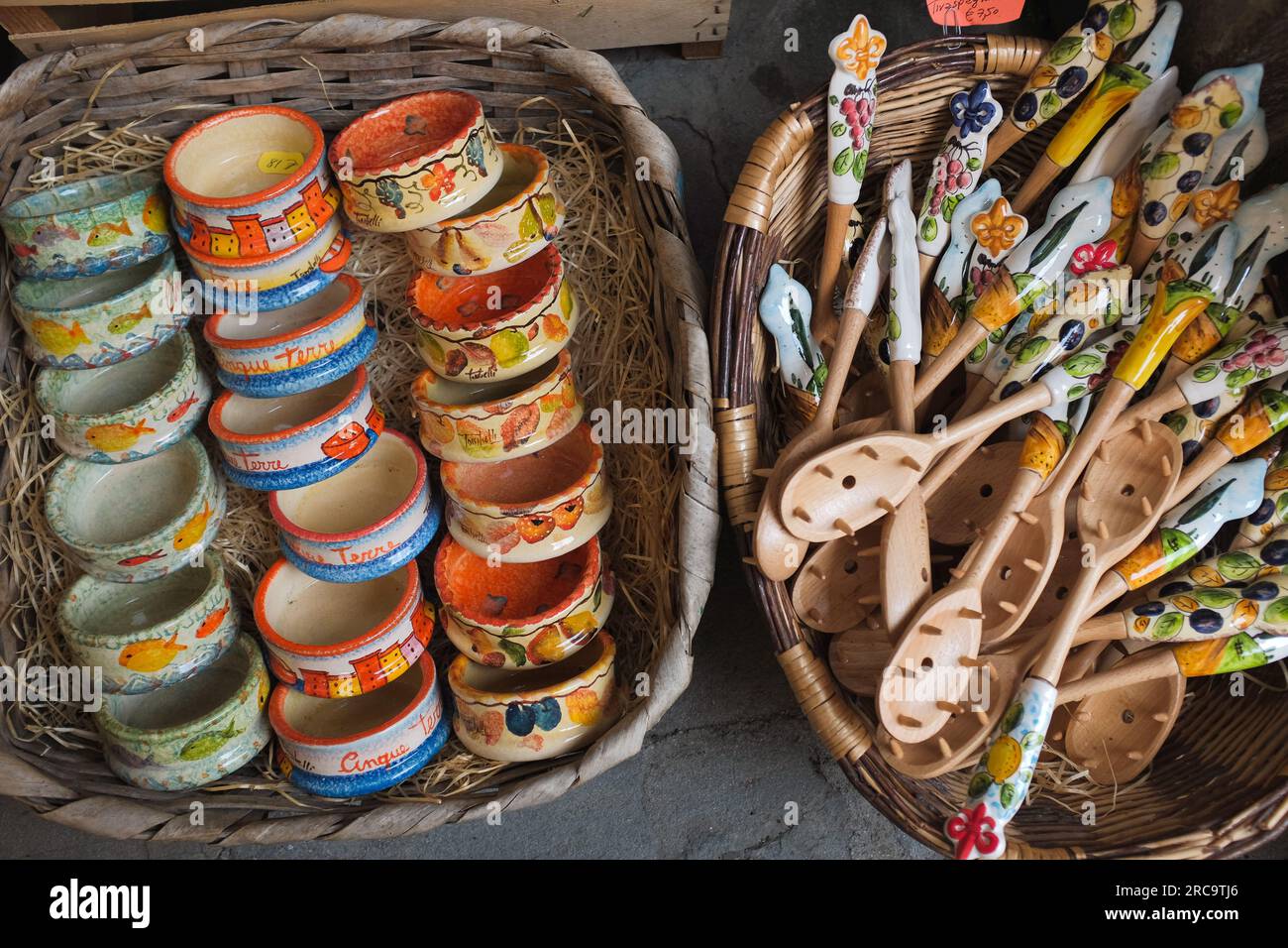 Cinque Terre, Italia - ciotole in ceramica colorata e cucchiai in legno su cesti. Souvenir locali venduti a Riomaggiore, una cittadina di mare sulla Riviera Italiana. Foto Stock
