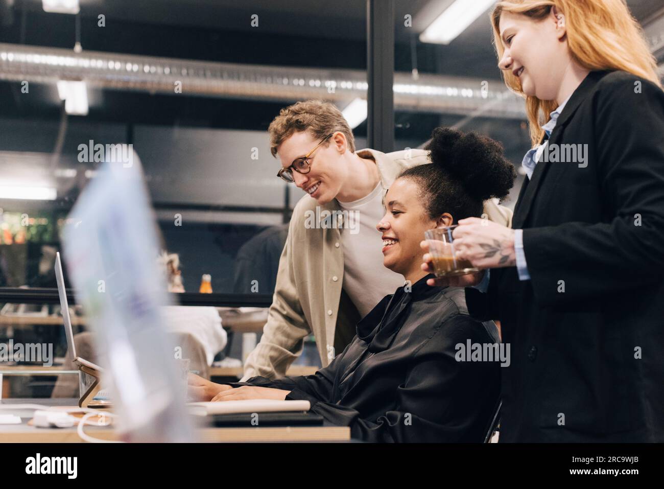 Sorridente team multirazziale che parla sul notebook mentre pianifica la strategia in ufficio Foto Stock