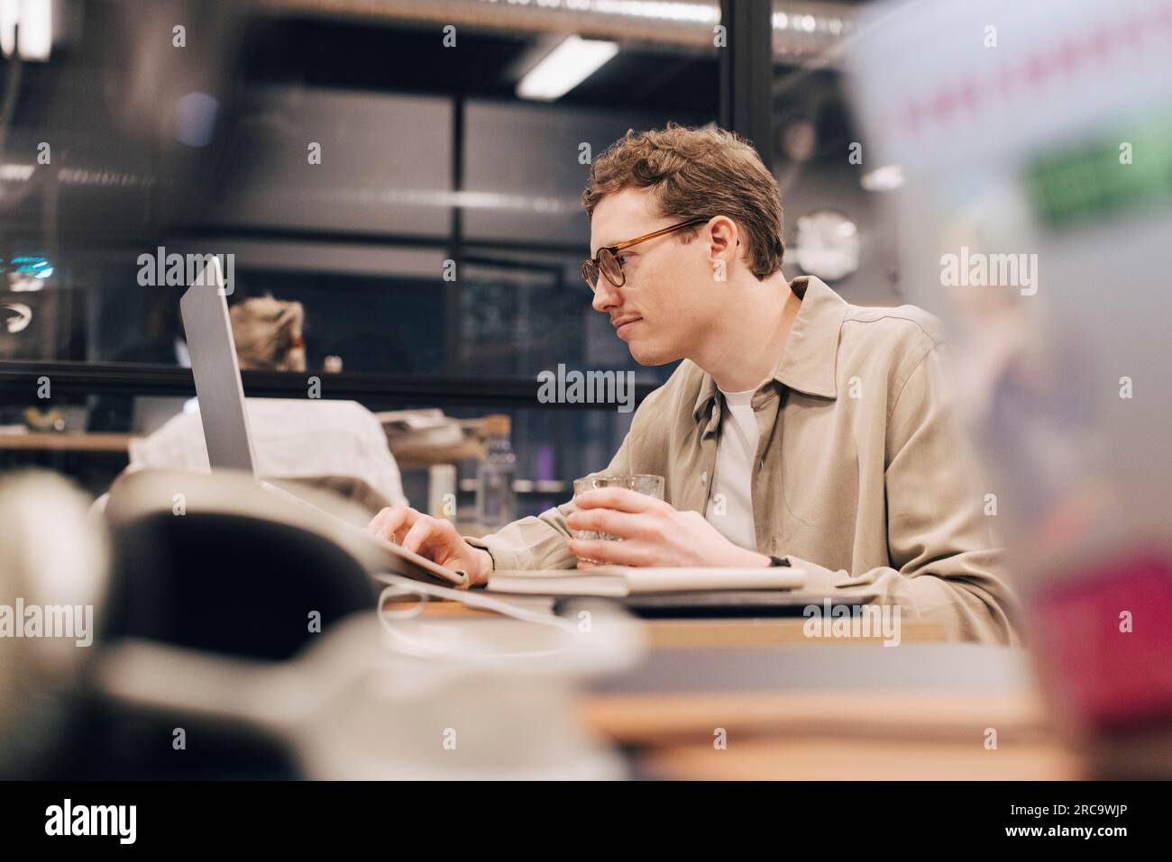 Uomo d'affari dedicato che utilizza un computer portatile alla scrivania in ufficio Foto Stock