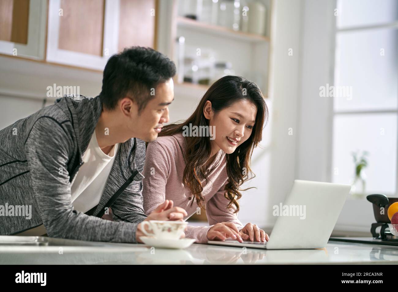 giovane coppia asiatica che utilizza il computer portatile insieme in famiglia cucina a casa Foto Stock