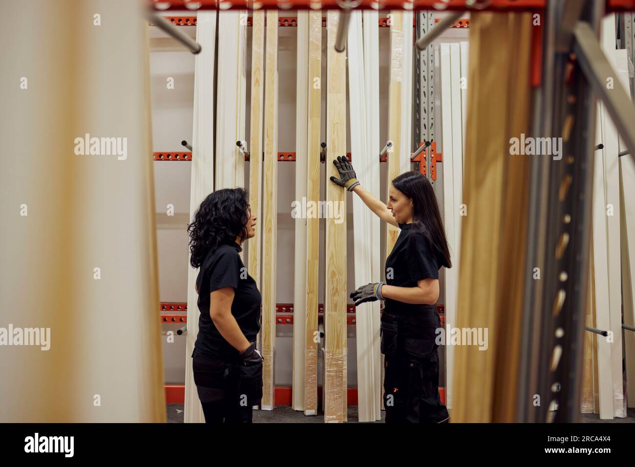 Colleghi femminili multirazziali che discutono sulle tavole a scaffale nell'industria del legname Foto Stock