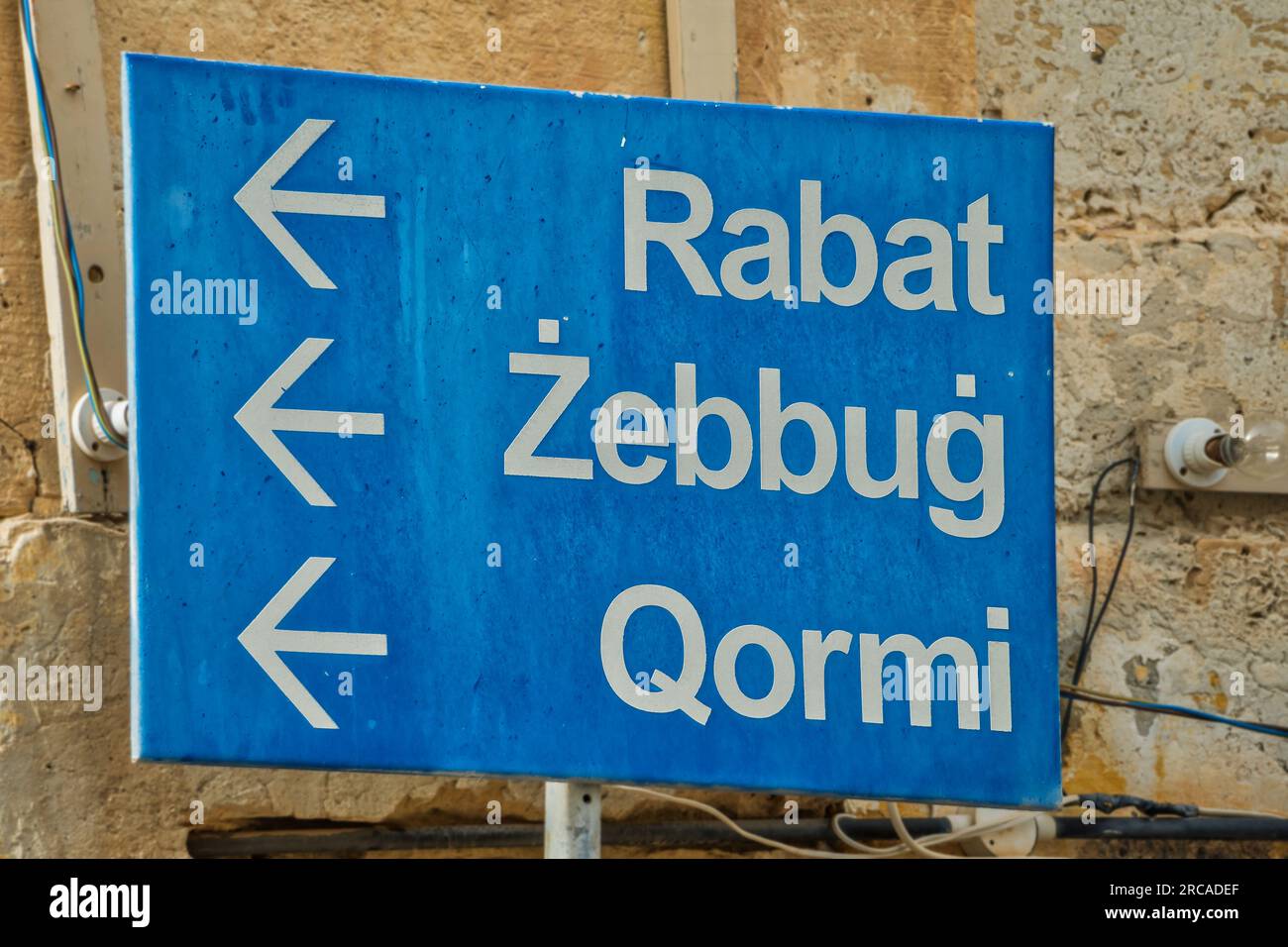 Segnale stradale maltese per Rabat, Żebbuġ e Qormi su un muro di calcare, Siggiewi, Malta. Foto Stock