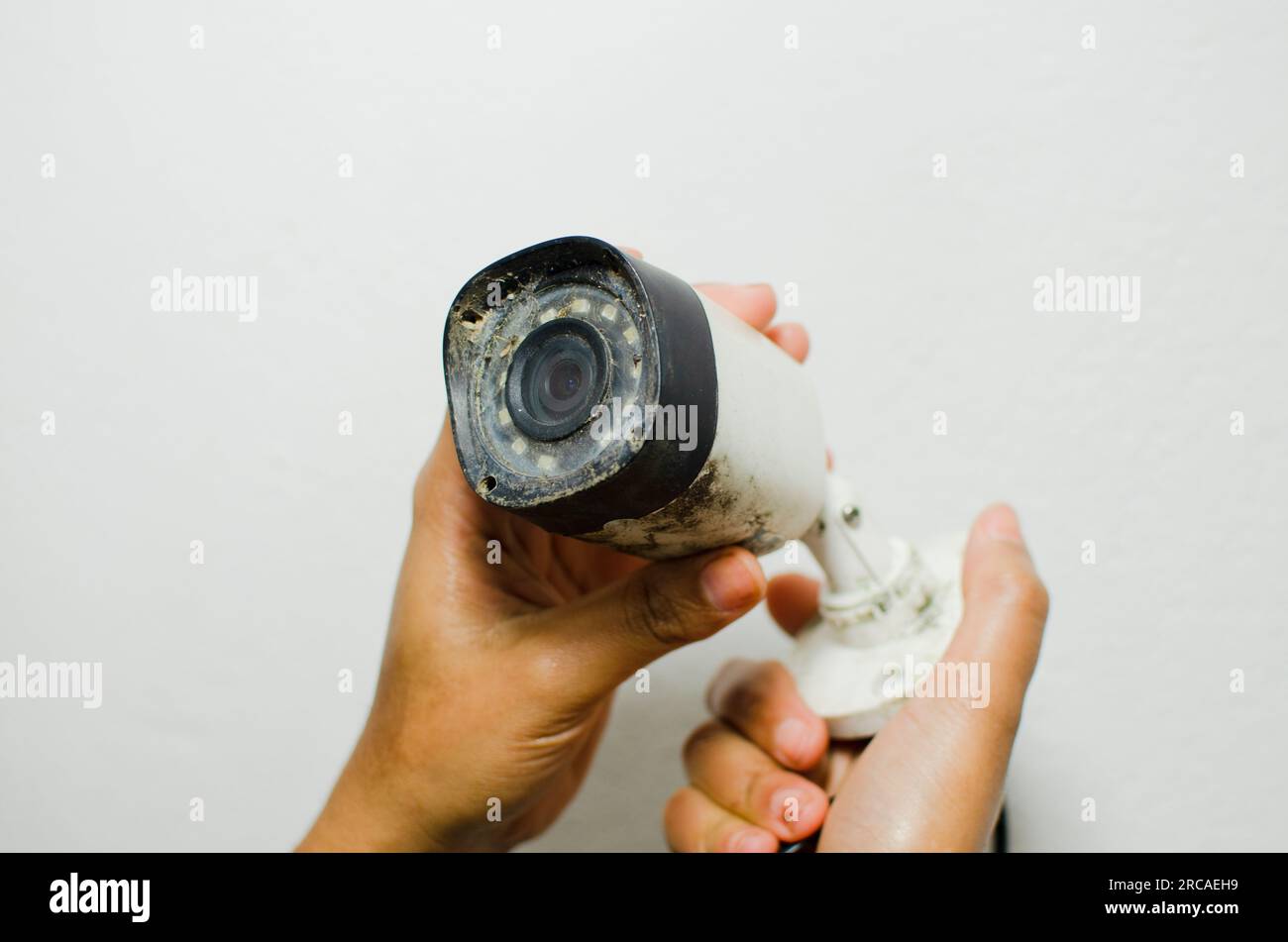 Un tecnico attento che esegue una manutenzione precisa su una telecamera di sicurezza bianca, rafforzando il concetto di protezione e sorveglianza. Foto Stock