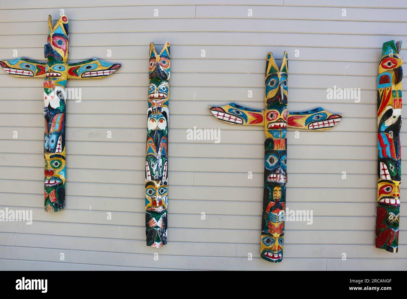 Pali totem dipinti in legno nativi appesi su un muro all'esterno del Ye Olde Curiosity Shop Pier 54 Seattle Washington State USA Foto Stock