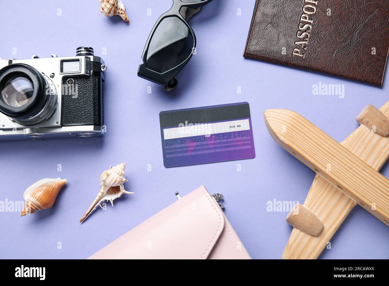 Composizione con carta di credito, passaporto, aereo in legno e macchina  fotografica su sfondo lilla Foto stock - Alamy