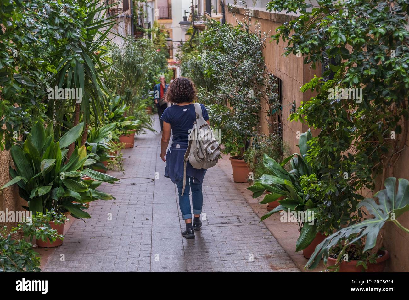 Donna che cammina in un vicolo nella città vecchia di Javea Foto Stock