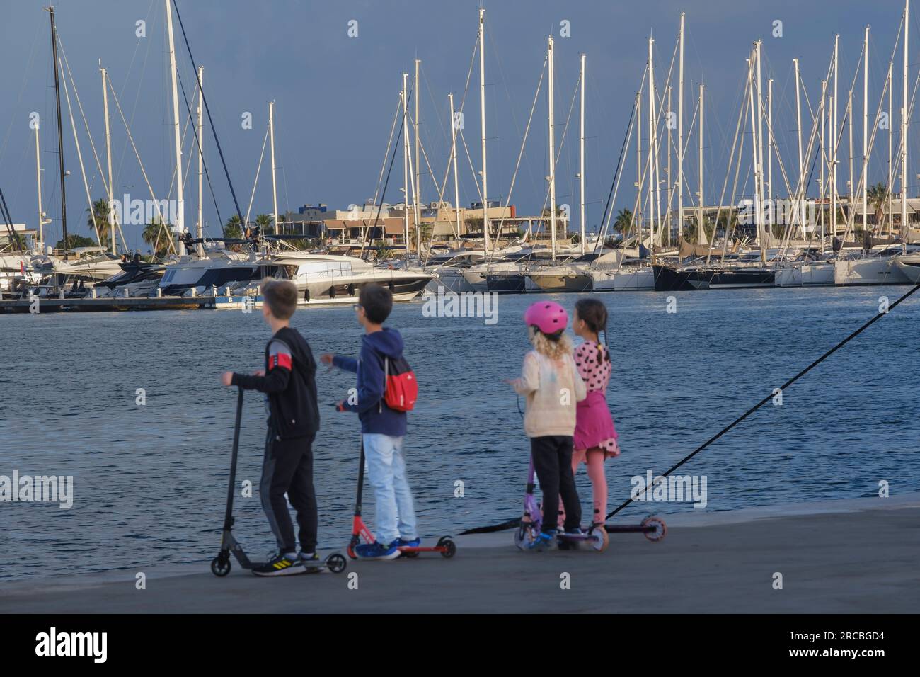 I bambini guardano il trambusto del porticciolo di Denia Foto Stock