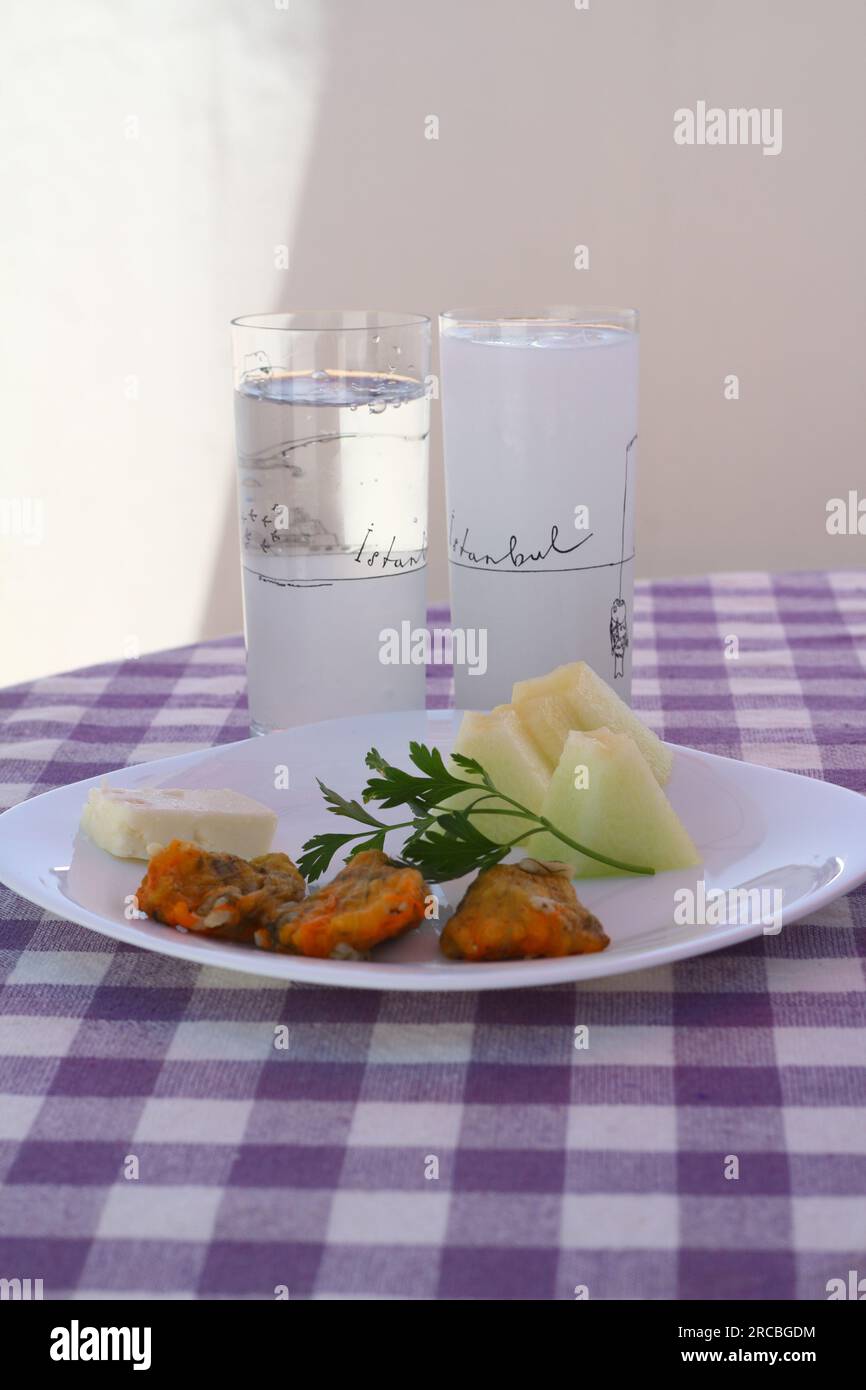 Bodrum, Turchia. 3 luglio 2017: Concetto di raki turco. Melone e formaggio con fioriture di zucchine ripiene. Un lettore di dischi vintage gioca in sottofondo. Foto Stock